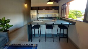 A modern kitchen with a central island, bar stools, and a view of the outdoors.