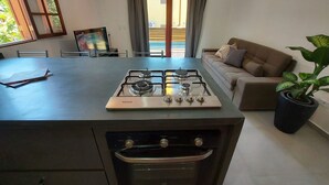 A compact kitchen with a gas stove, oven, and a dining area with a table and chairs.