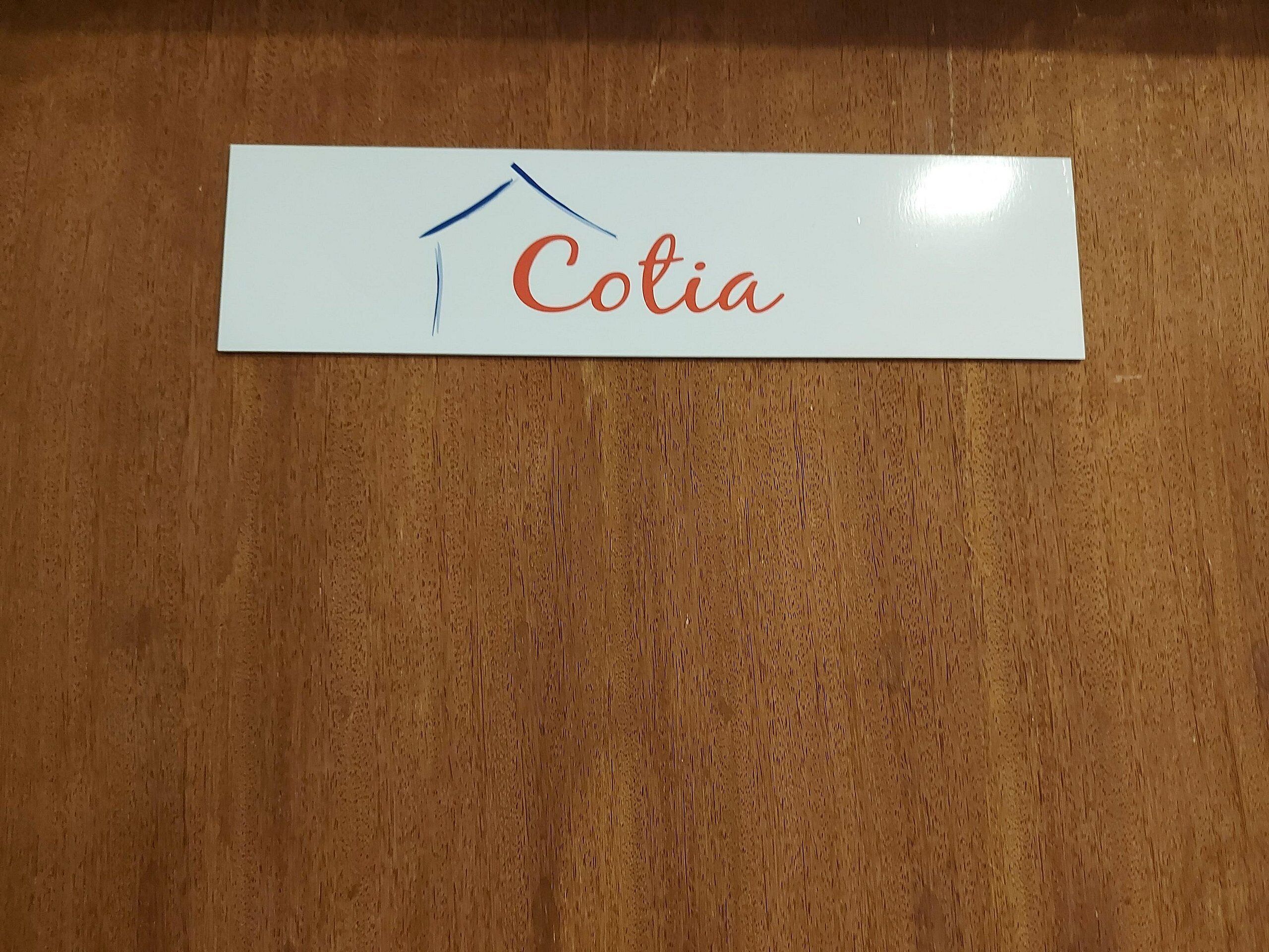 A white sign with the name "Cotia" and a simple house drawing.