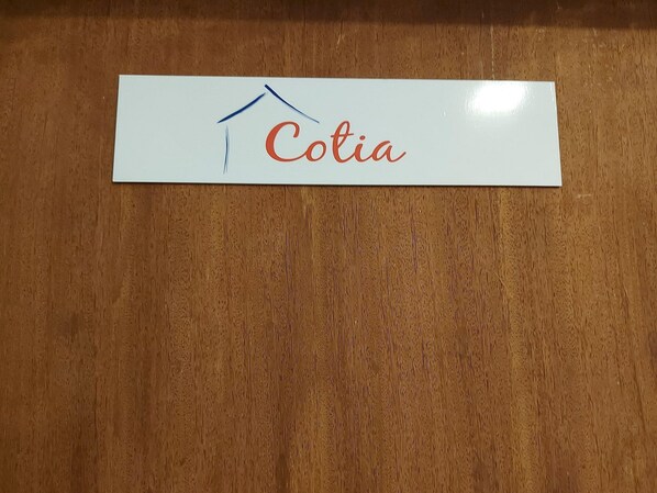 A white sign with the name "Cotia" and a simple house drawing.