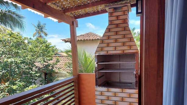 Ein Barbereich mit offenem Backsteinofen und einer darüber hölzernen Pergola.