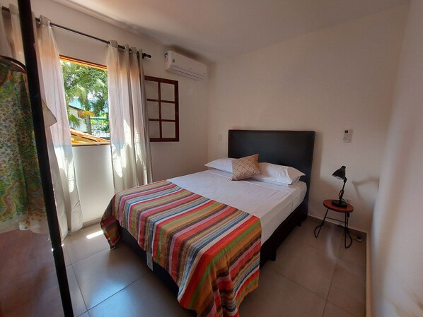 A bedroom with a bed, a bedside lamp, and a window with curtains.