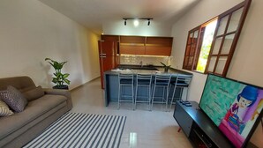 Un saló modern amb un sofà, una televisió i una cuina al fons.