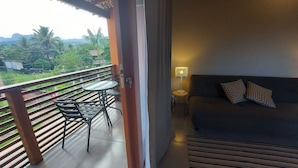 A balcony with a table and chairs, a sofa with patterned pillows, and a lamp. - Cepilho - Cosy Flat Near the Beach with kitchen, private BBQ, pool (Paraty)