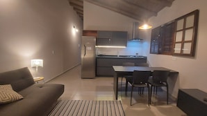 A compact living space with a kitchenette, a dining area, and a sofa. - Cepilho - Cosy Flat Near the Beach with kitchen, private BBQ, pool (Paraty)