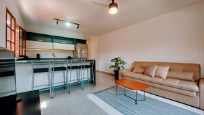 Una cucina moderna con sgabelli da bar, un divano e un tavolino da caffè in un soggiorno.