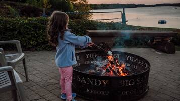 A child roasting marshmallows over a fire pit labeled "SANDY BIG SAN RESORT".