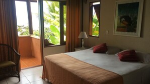 Una habitación de hotel con una cama, una silla, una mesita de noche con lámpara y un cuadro en la pared.