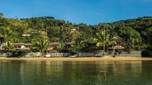 Zona costera con casas en una ladera, una playa y una extensión de agua.
