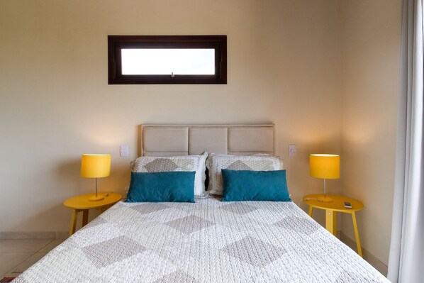A bedroom with a bed, two bedside lamps, and a window above the bed.