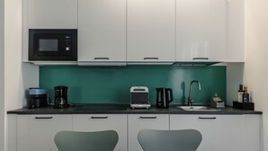 Une cuisine moderne avec des meubles blancs, un four à micro-ondes, une machine à café, un grille-pain et un évier.
