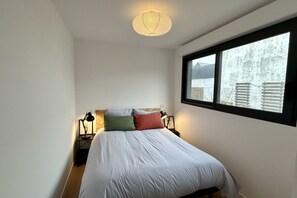 Une chambre à coucher avec un lit, des lampes de chevet, une fenêtre et un luminaire suspendu.