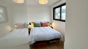 Un dormitorio con cama, lámparas de noche, ventana y lámpara de techo.