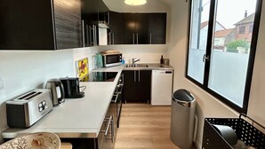 Una cocina compacta equipada con microondas, tostadora, lavamanos y un cubo de basura.
