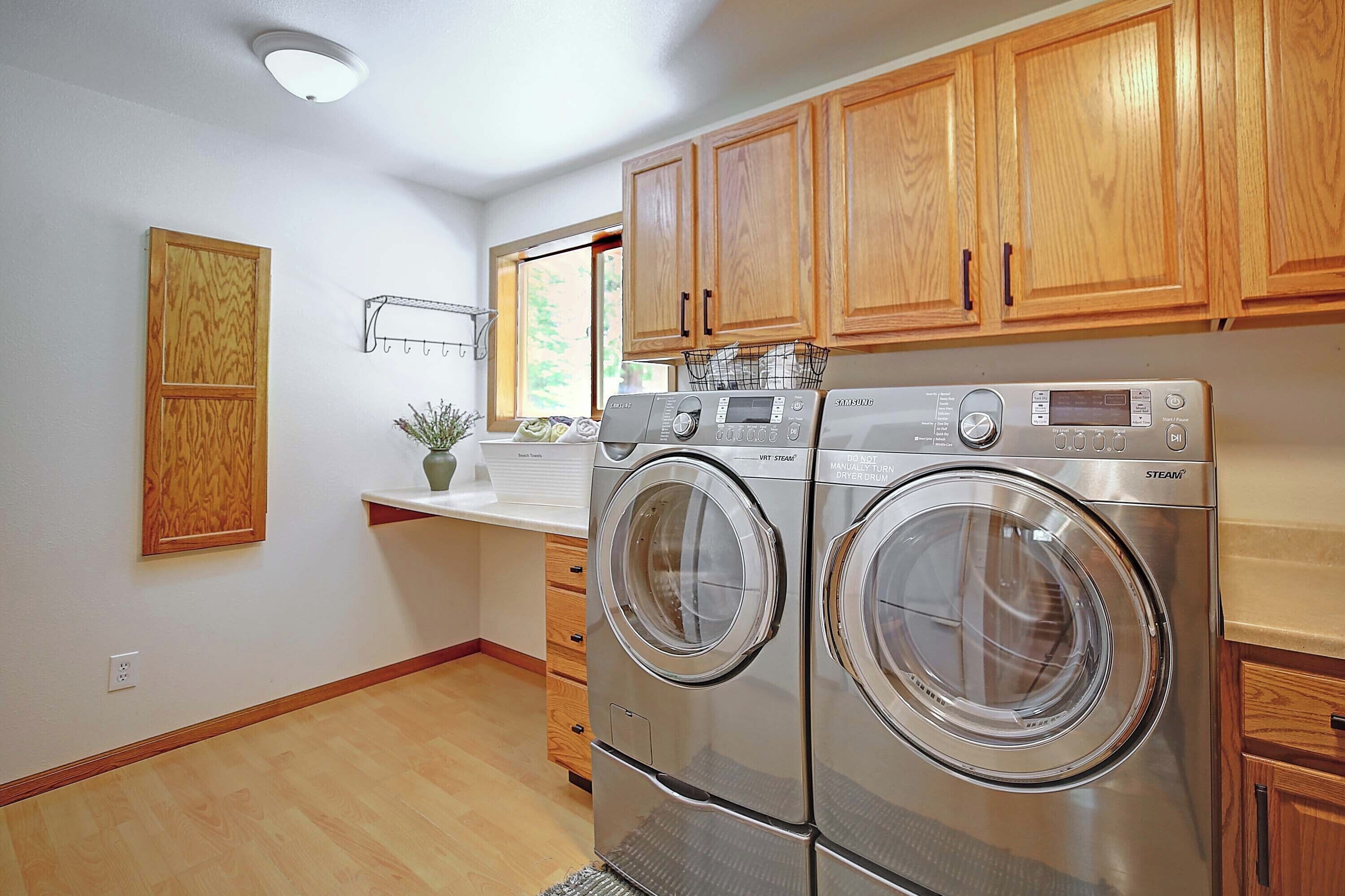 Une cuisine moderne avec des meubles en bois, des appareils en acier inoxydable et un lave-linge et un sèche-linge intégrés.