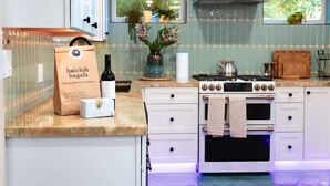 Cocina con armarios blancos, estufa y ventana con plantas.