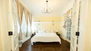 Ein Schlafzimmer mit einem großen Bett, einer Chandelier und einem Fenster mit Vorhängen.