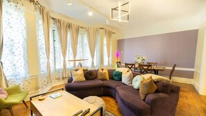 Ein modernes Wohnzimmer mit einem Ecksofa, einem Couchtisch und einem Esstisch mit Stühlen.