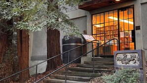 Una entrada de edificio con una escalera que lleva a un balcón en un segundo piso.