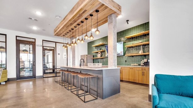 Une cuisine moderne avec un îlot central, des tabourets de bar et un canapé de couleur turquoise.