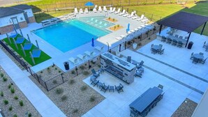 Un espace piscine sur le toit, doté de plusieurs coins salon, d’un foyer extérieur et d’une terrasse couverte.