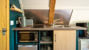 A compact kitchenette with a microwave, toaster, and sink.