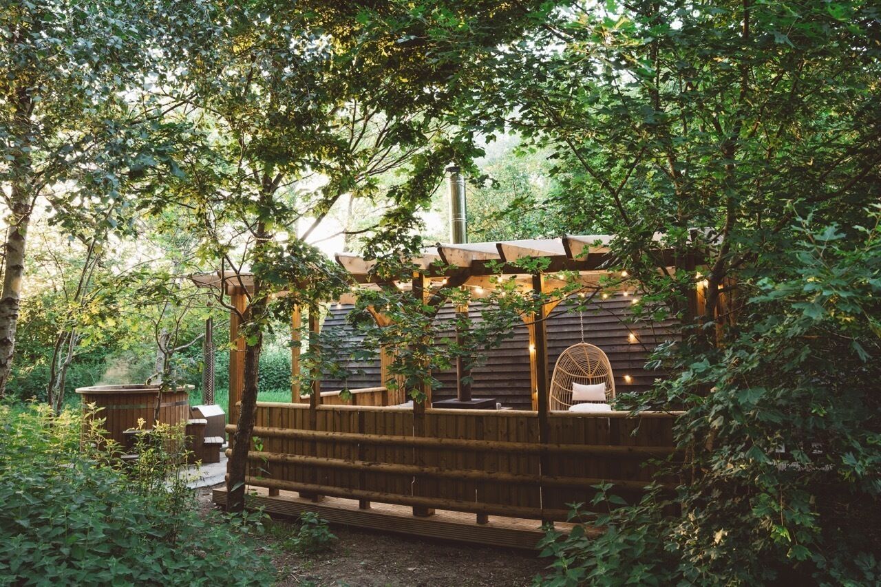 Une terrasse en bois avec un espace salon, entourée d’arbres.
