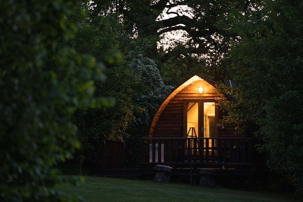 A cozy wooden cabin with a porch, surrounded by dense trees.