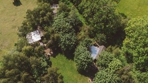 An aerial view of a rural property with two buildings surrounded by dense greenery.