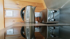 A kitchen with a stainless steel kettle and toaster on a reflective countertop.