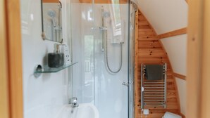 A compact, modern bathroom with a glass shower enclosure, a built-in sink, and a towel rack.