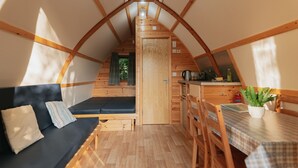 A cozy attic room with a sofa, a dining table, and a kitchenette.