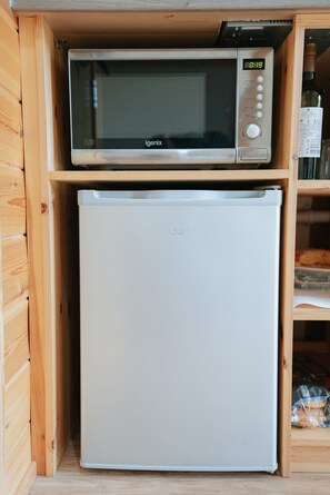 Eine kleine Küchenzeile mit einer Mikrowelle und einem weißen Kühlschrank.
