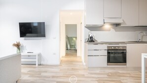 A modern kitchen with a built-in oven, a flat-screen TV, and a minimalist design. - Alice House - Cagliari (Cagliari)