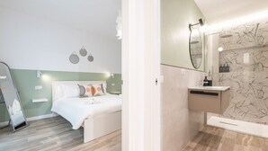 A bedroom with a bed, a bedside table, and a nightstand. There is a mirror above the sink in the bathroom. - Alice House - Cagliari (Cagliari)