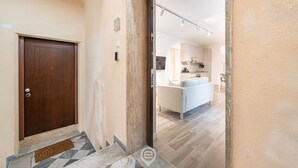 A modern interior with a wooden door, a kitchen area, and a living space with a sofa. - Alice House - Cagliari (Cagliari)