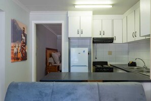 A compact kitchen with white cabinets, a refrigerator, and a stove.