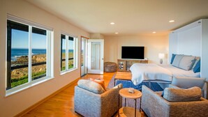Un dormitorio con cama, televisión, sofá y vistas al océano.