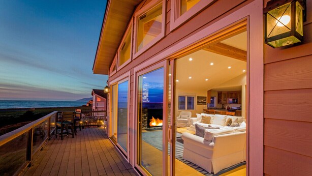 Una casa moderna con terraza, chimenea y vista al océano.