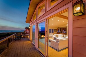 Una casa moderna con terraza, chimenea y vista al océano.