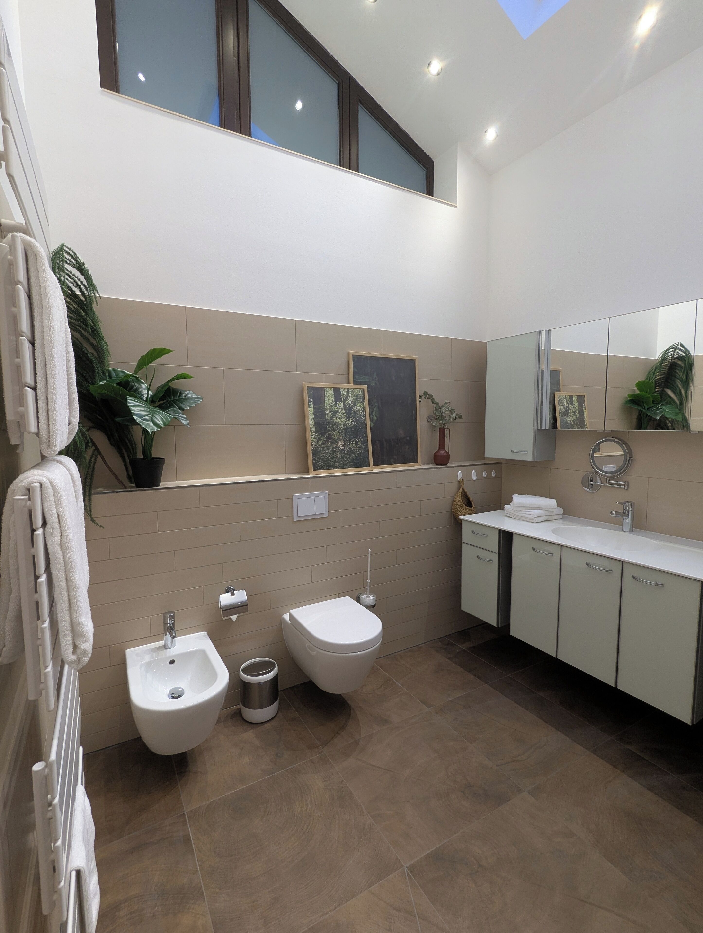 A modern bathroom with a bidet, toilet, sink, and towel rack.