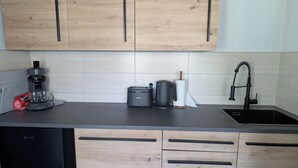 A modern kitchen with wooden cabinets, a black countertop, a coffee maker, a toaster, and a sink.