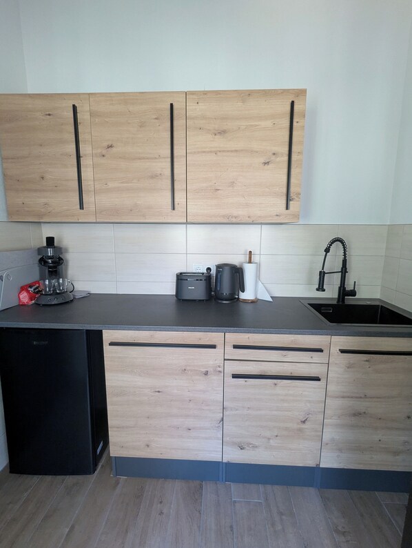 Una cocina moderna con armarios de madera, encimera negra, cafetera, tostadora y fregadero.