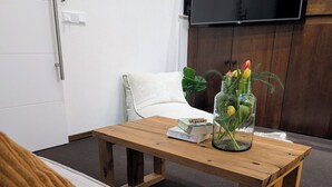 A cozy living room with a wooden coffee table, a white sofa, a fluffy white rug, and a glass vase with flowers.