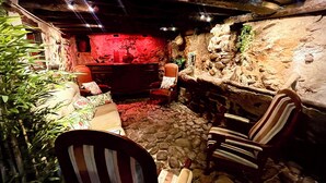 Un interior acogedor y rústico con paredes de piedra, un banco de madera y un fondo iluminado en rojo.