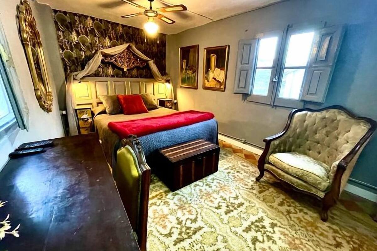 A room with a bed, a chair, a table, and a patterned rug.