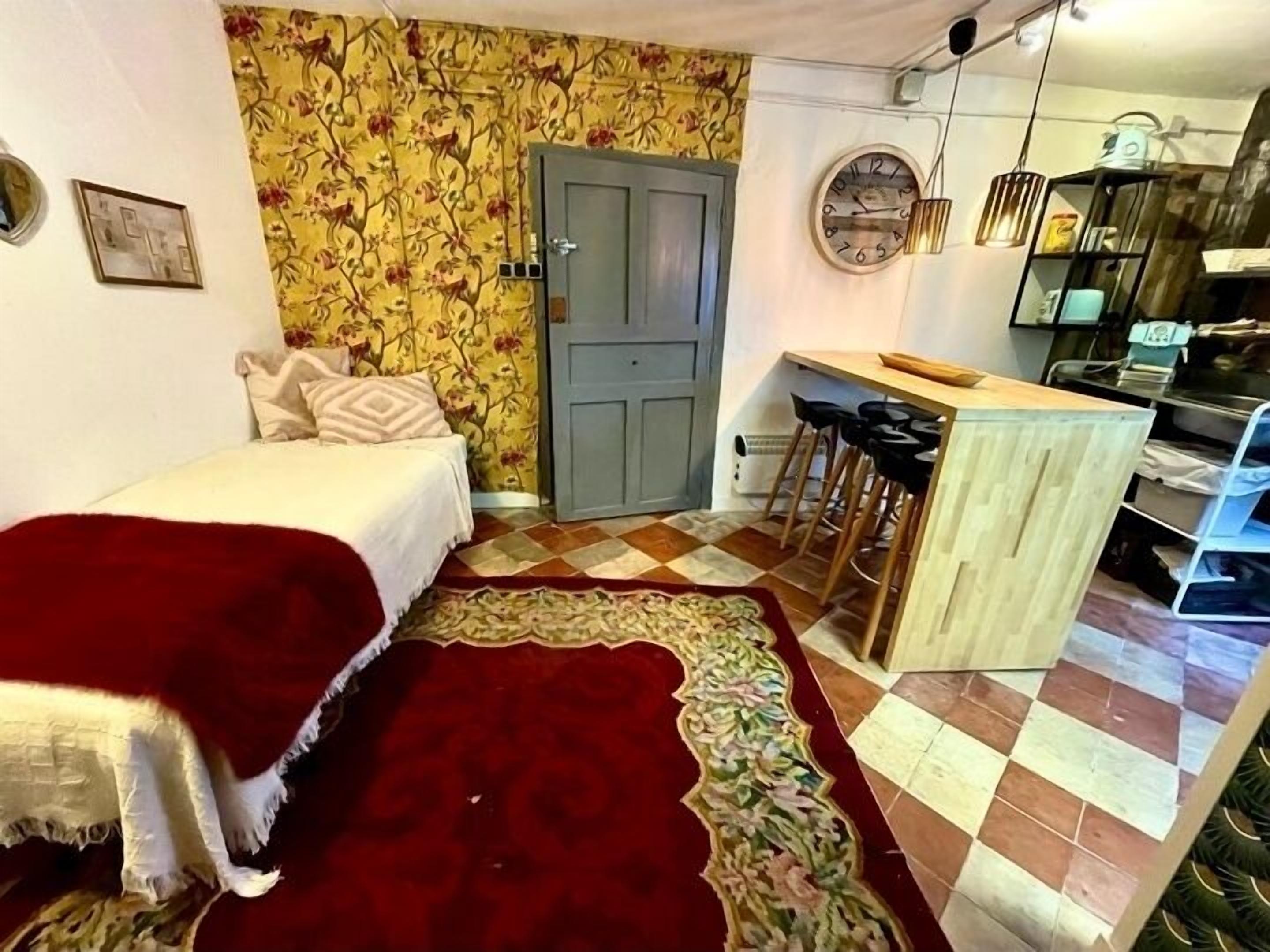 A compact room with a bed, a small kitchenette, and a dining area.