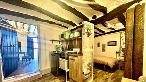 Habitación rústica con vigas de madera a la vista, una kitchenette, una cama y un comedor con vistas.