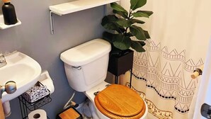 Un baño pequeño con inodoro blanco, lavamanos y estantes con cestas.