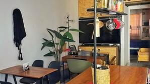 Un espacio habitable compacto con comedor, televisor y estante con utensilios de cocina.